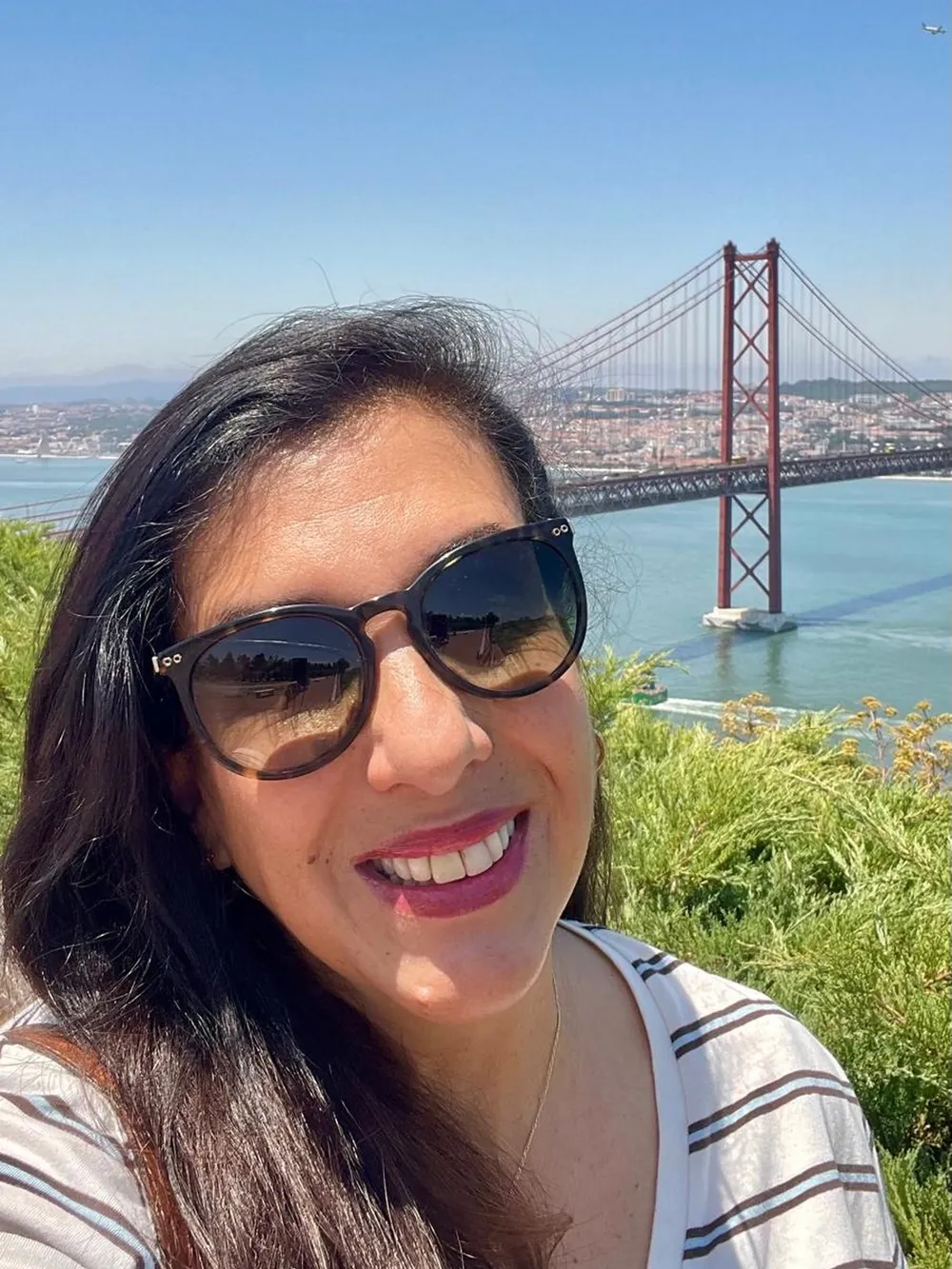 Valéria Januzzi, guia turística brasileira em Lisboa, com a Ponte 25 de Abril ao fundo